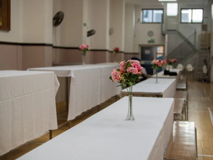 Banquet hall set up with tables and rose centrepieces, ready for guests